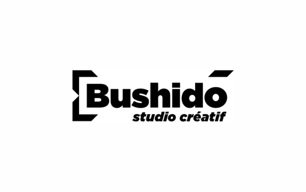 Black and white logo of Bushido Studio Créatif, highlighting bold typography and brackets, representing a creative studio specializing in graphic design.
