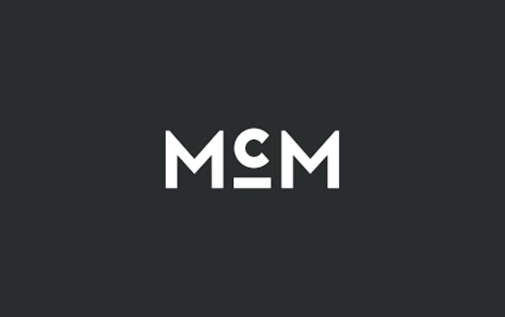 McMillan agency logo featuring bold white letters 'MCM' on a dark background.